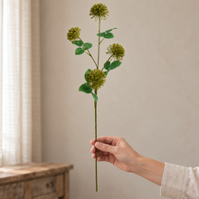 Single Green Fireball Spray faux stem with four flower heads held in a hand